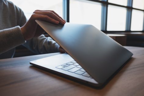 Close-up of hands closing a laptop — representing a pause in progress, not giving up on a goal.