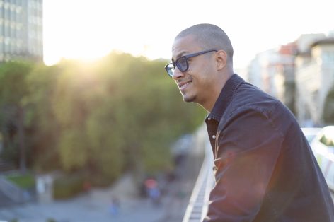 Man smiling and looking out over a city skyline at sunset — representing visible, tangible growth